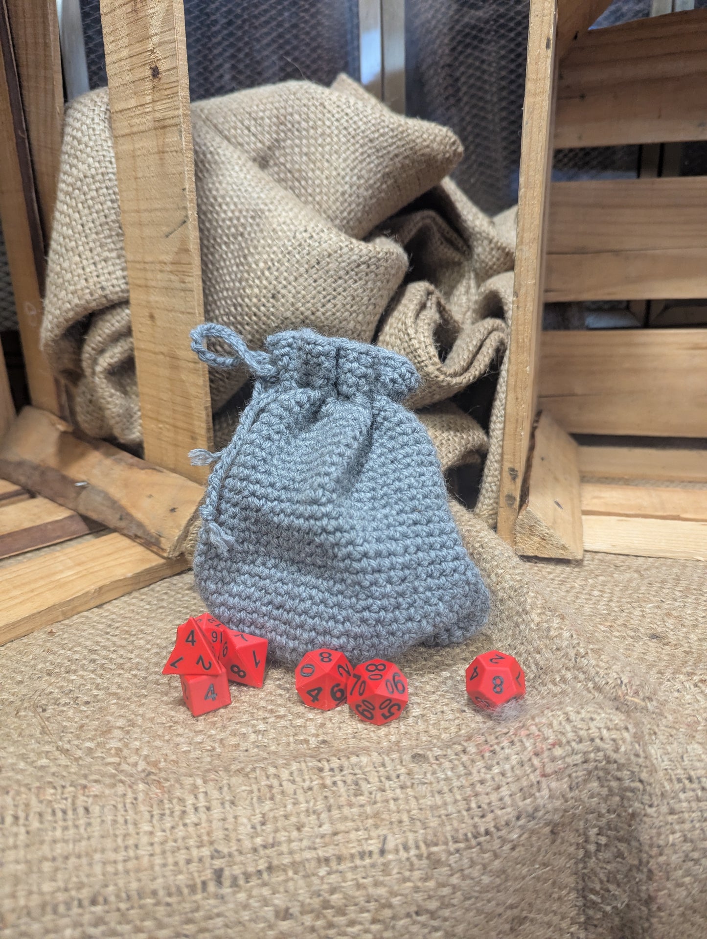 Gray drawstring bag with red dice on a textured surface