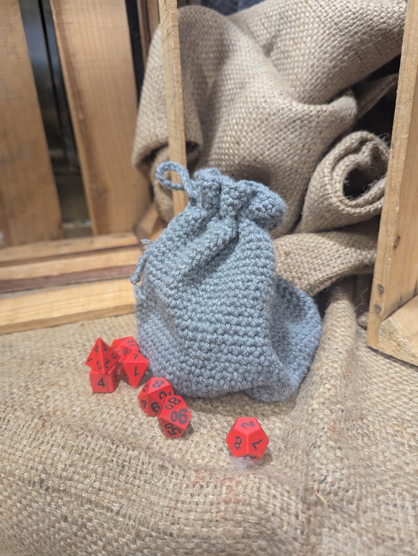 gray drawstring bag with red dice on a textured surface