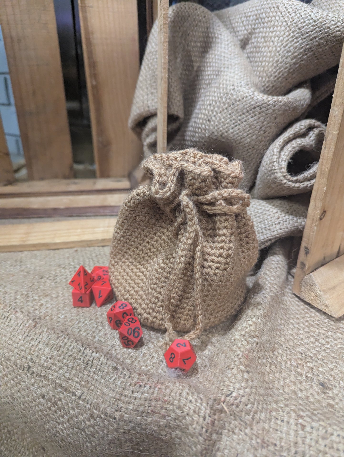 burlap crochet drawstring bag with red dice on a textured surface