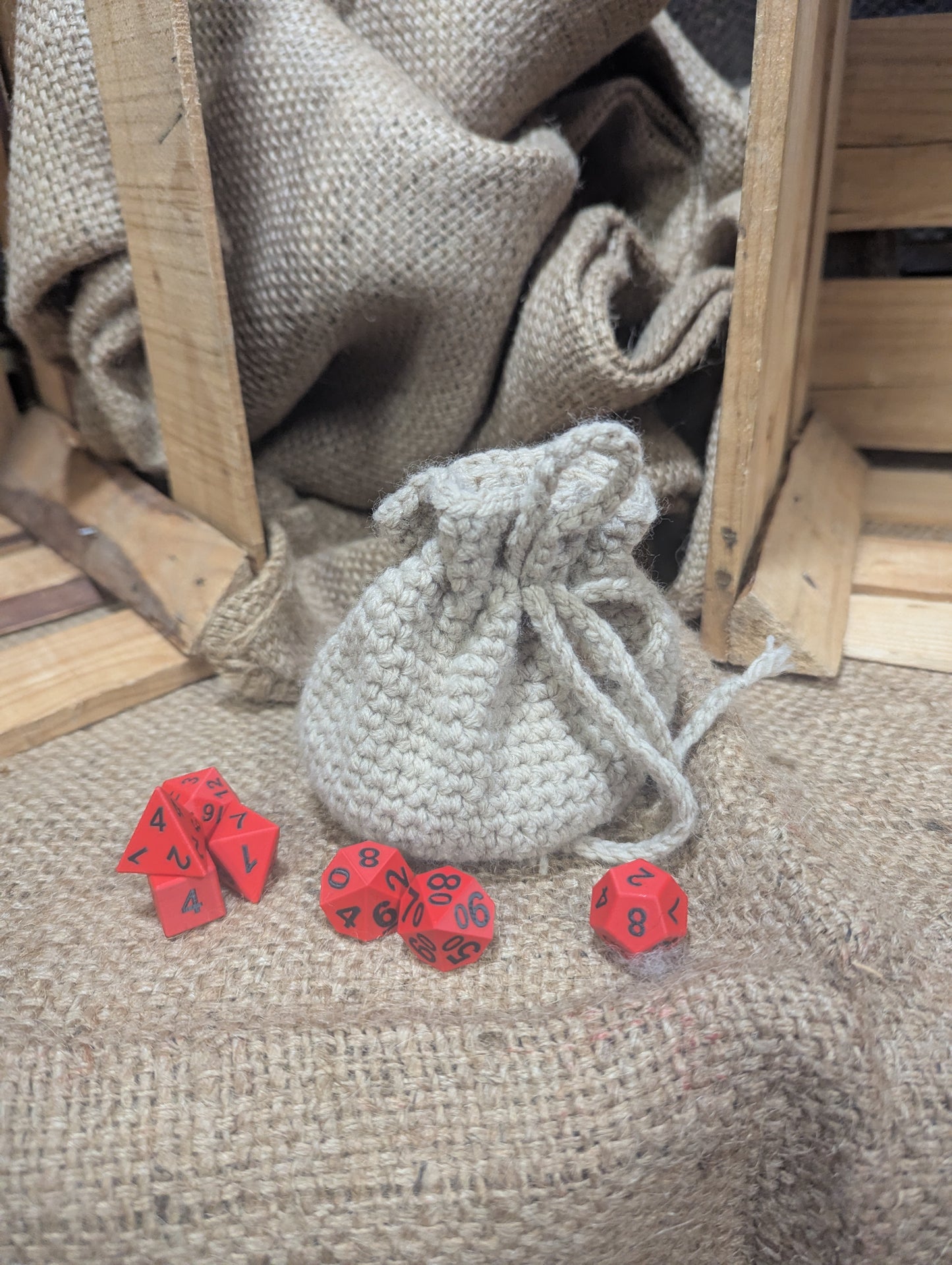Cream colored Drawstring bag with red dice on a rustic wooden and burlap background