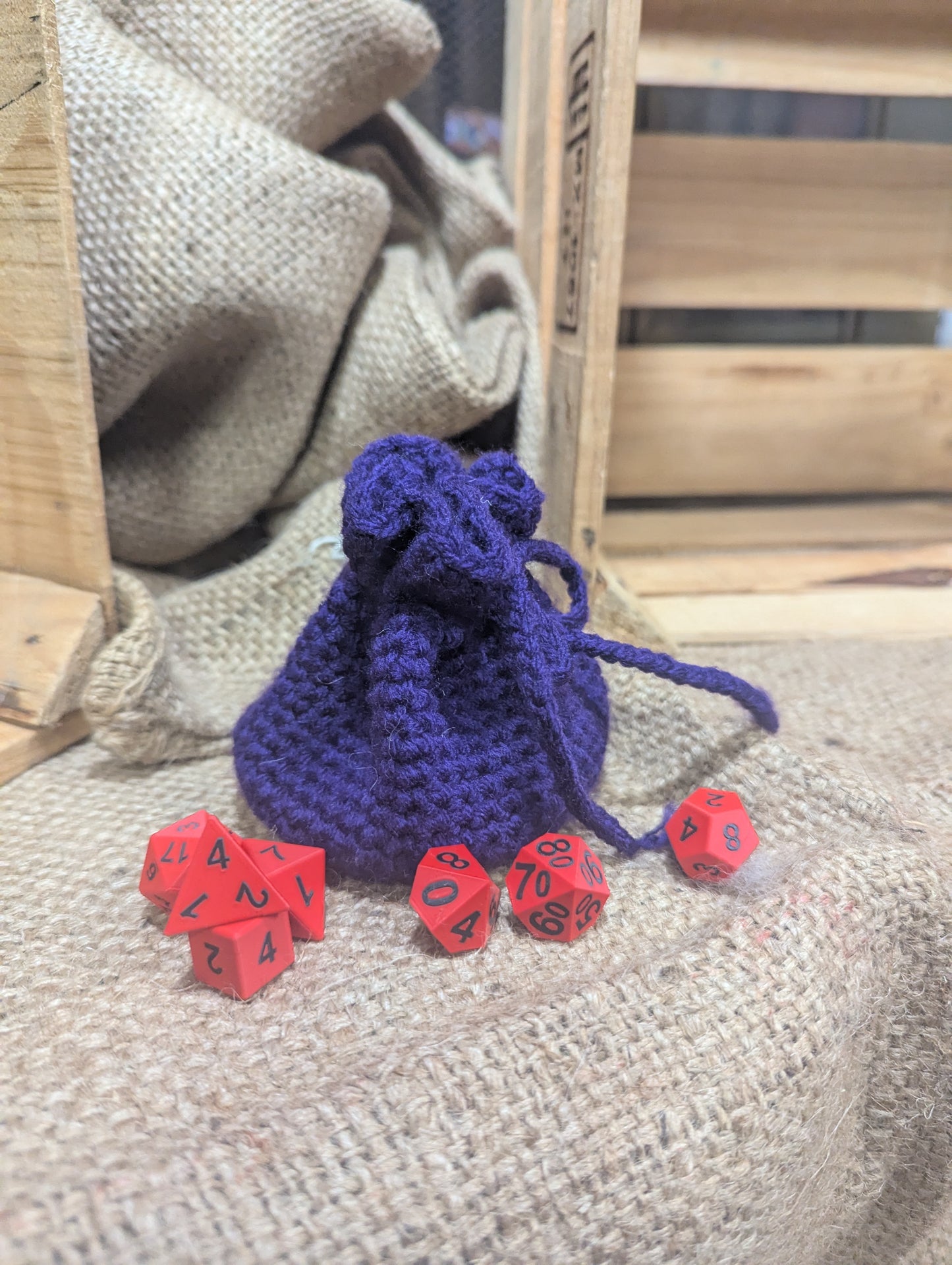 purple drawstring bag with red dice on a textured surface
