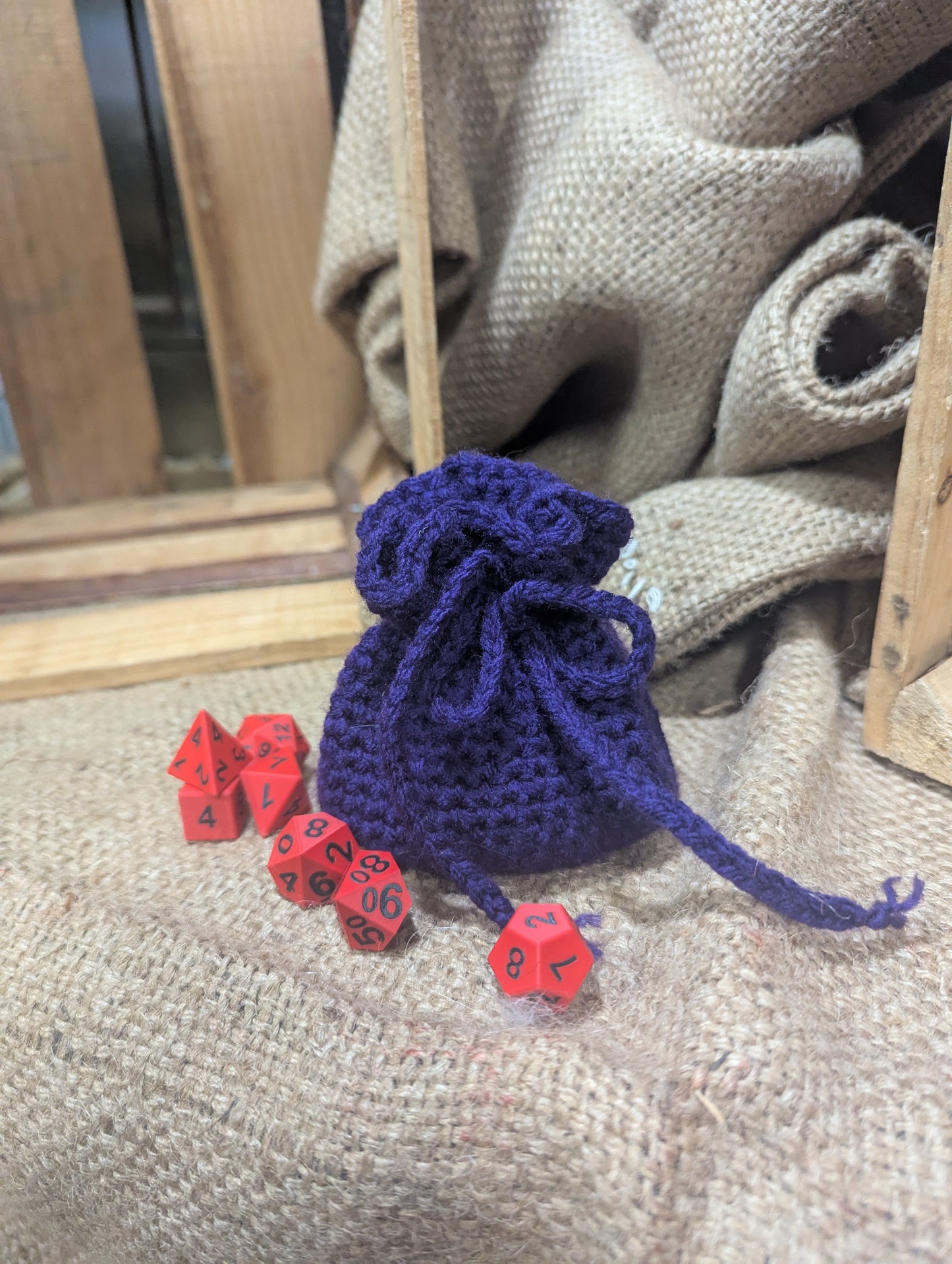 Purple drawstring bag with red dice on a textured surface