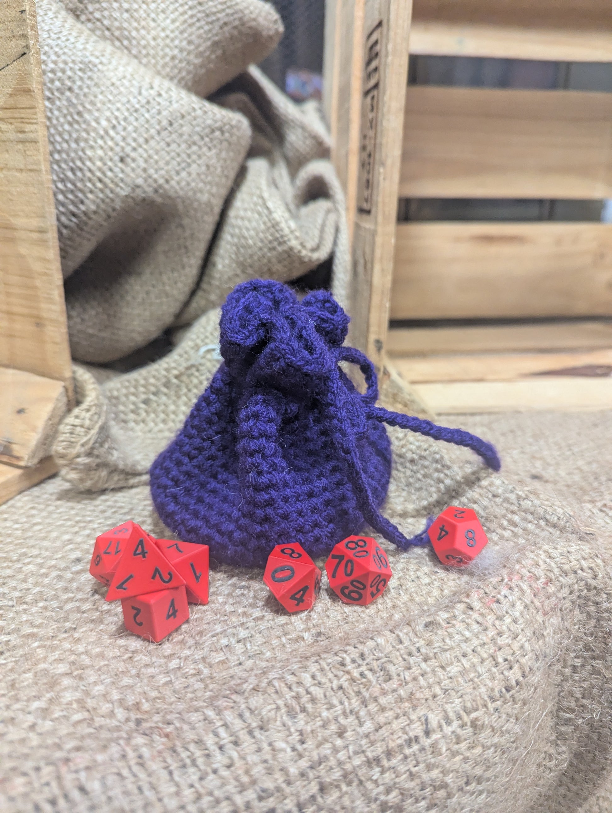 purple drawstring bag with red dice on a textured surface